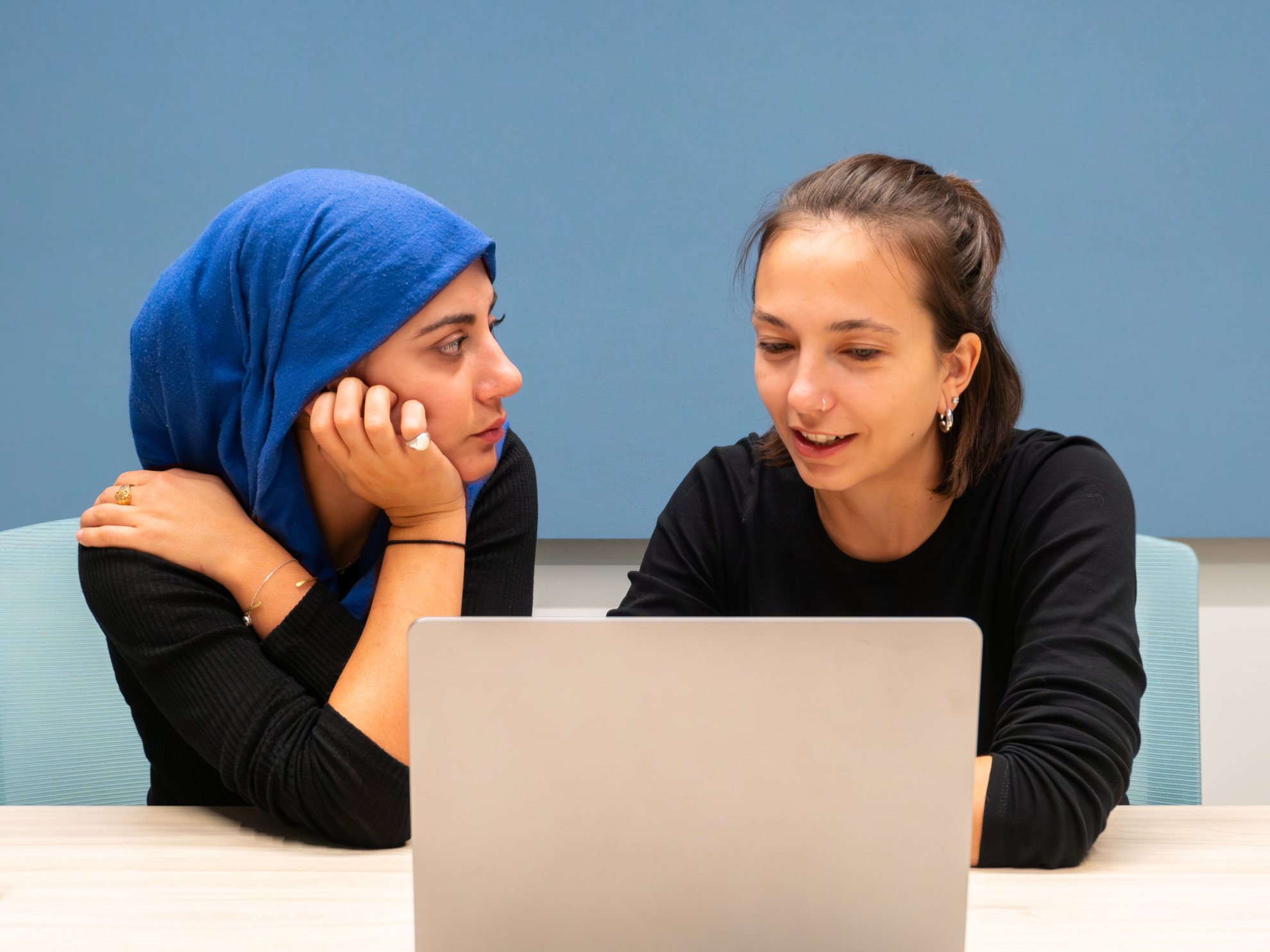 Due donne che guardano un laptop, una con il velo