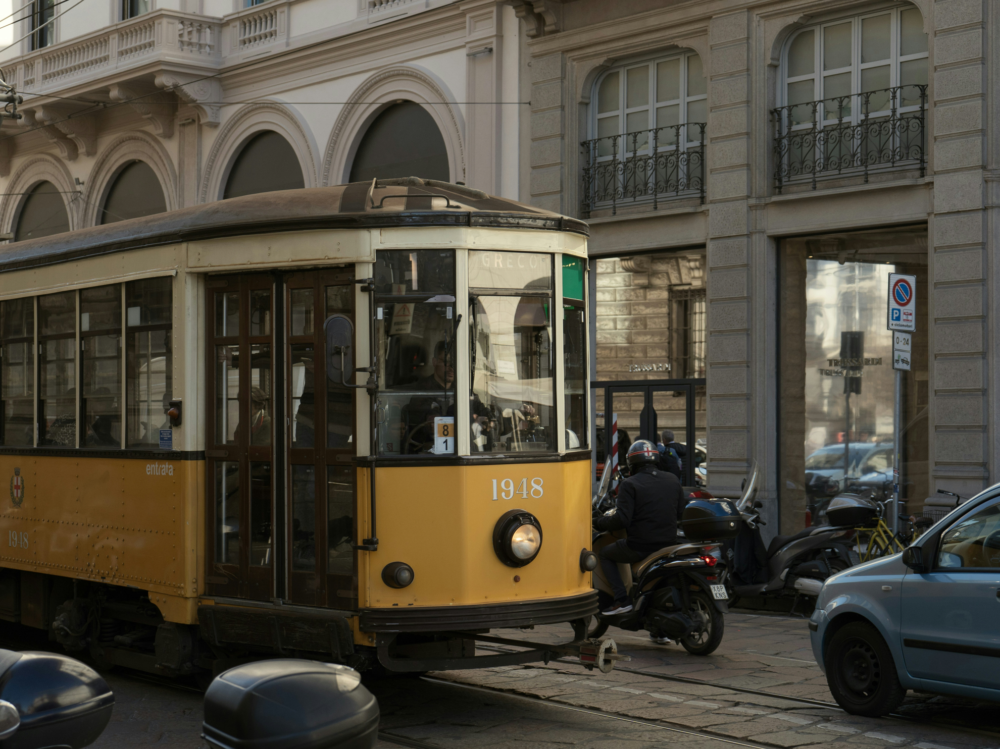 Tram storico giallo in transito in una strada cittadina.