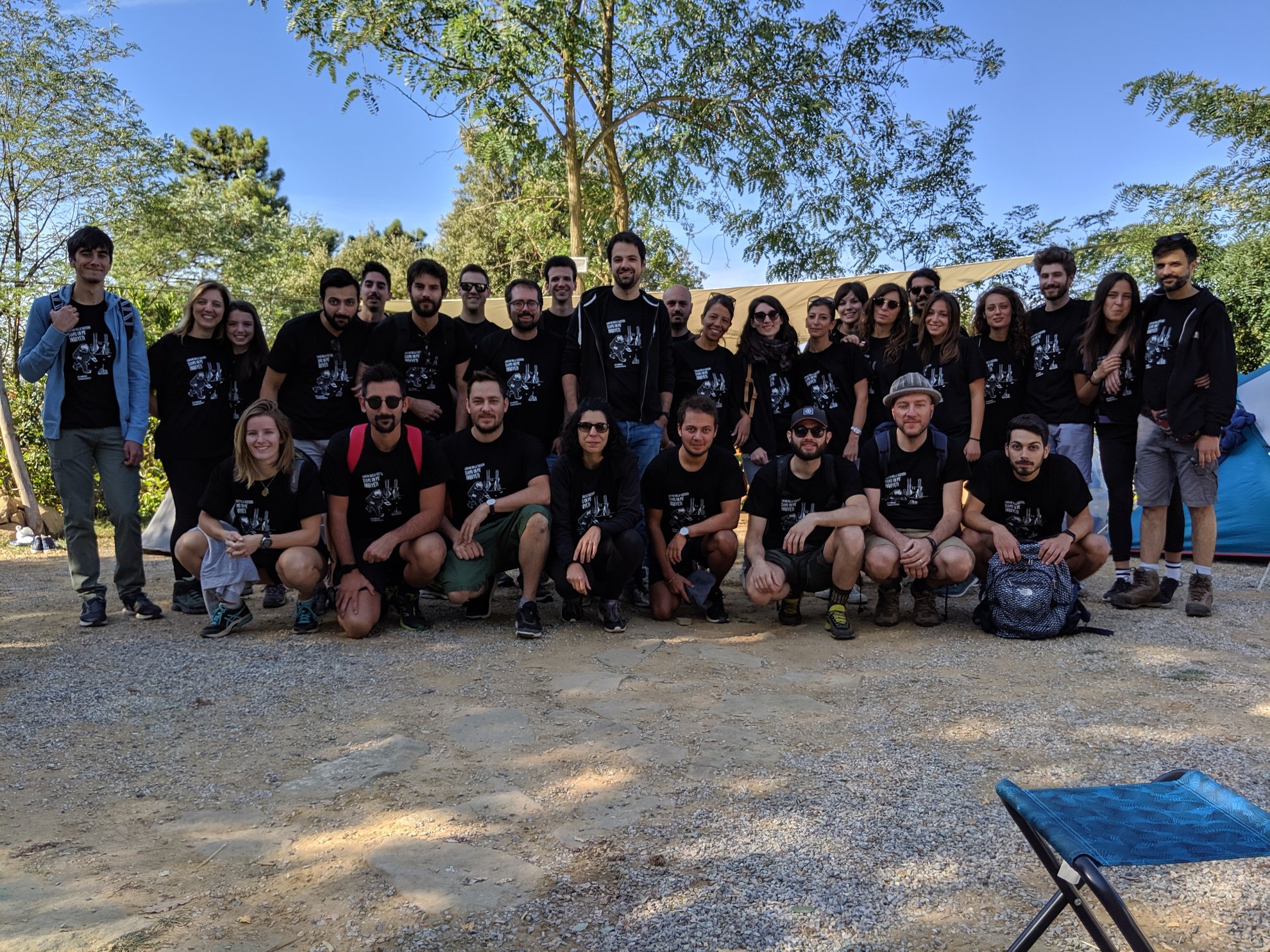 Gruppo di persone in piedi e sedute, molti indossano magliette nere.