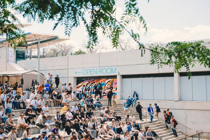 Tante persone sedute all'aperto su una scalinata di cemento