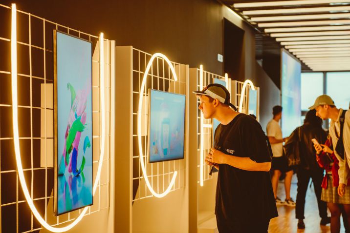 Persone osservano opere d'arte digitale appese al muro