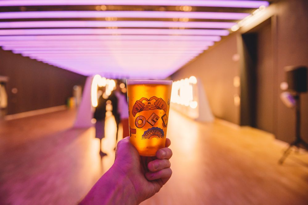 Bicchiere di birra in primo piano su sfondo di un'ampia stanza con luci al neon